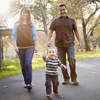 parents with toddler smiling and walking outside on a pretty day